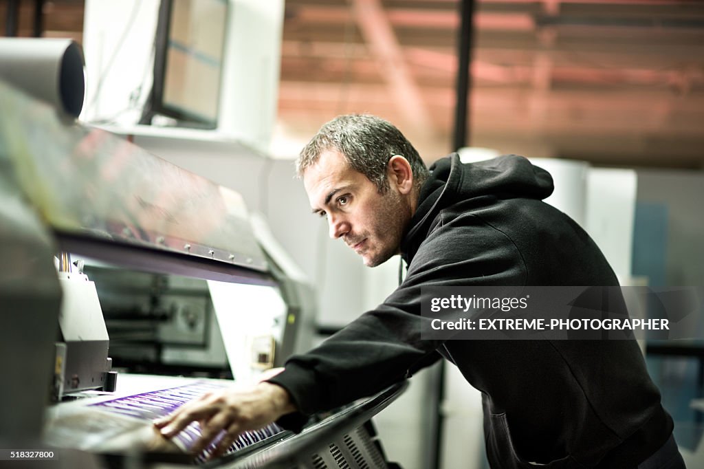 Male worker operating on industrial printer