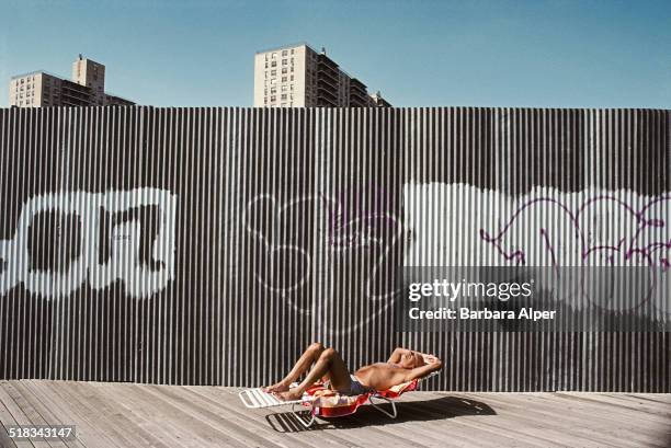 Man sunbathes on the boardwalk at Brighton Beach, Brooklyn, New York City, USA, September 1991.