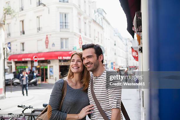 france, paris, portrait of happy couple having fun - couple paris stock-fotos und bilder