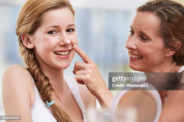 mother applying face cream on her daughter's nose - kids in undies stock-fotos und bilder