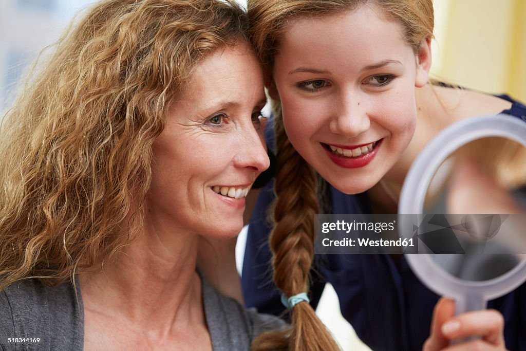Portrait of mother and daughter looking at mirror