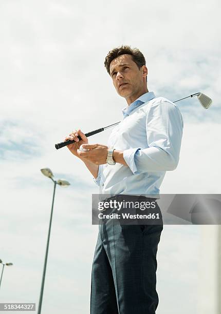 business man with golf club and ball - licht von unten stock-fotos und bilder