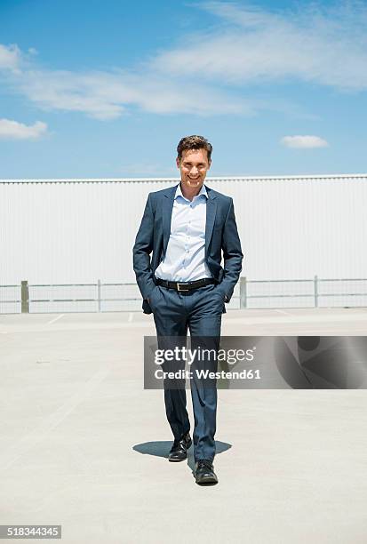 smiling business man walking on parking level - mani in tasca foto e immagini stock