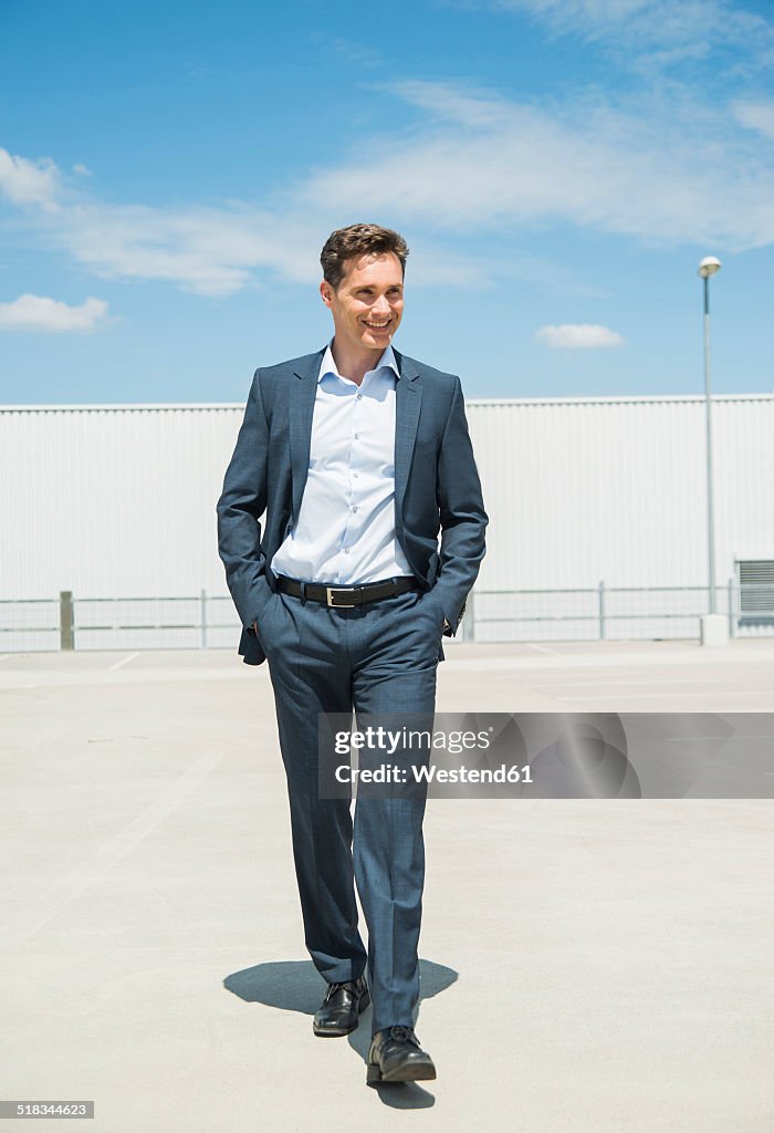 Smiling business man walking on parking level