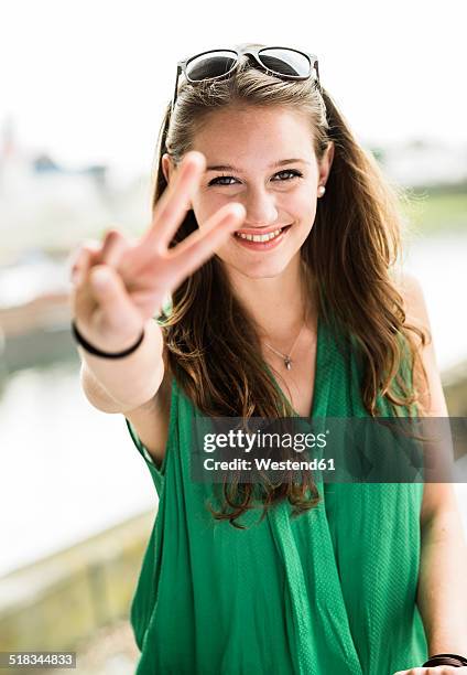 portrait of smiling teenage girl showing victory sign - friedenszeichen handzeichen stock-fotos und bilder