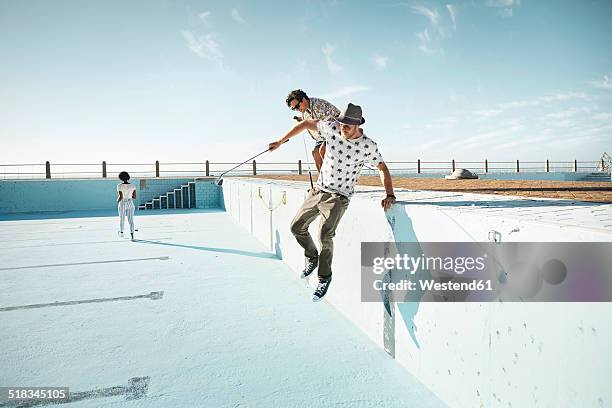 friends playing urban golf in empty swimming pool - fashion woman jumping stock-fotos und bilder