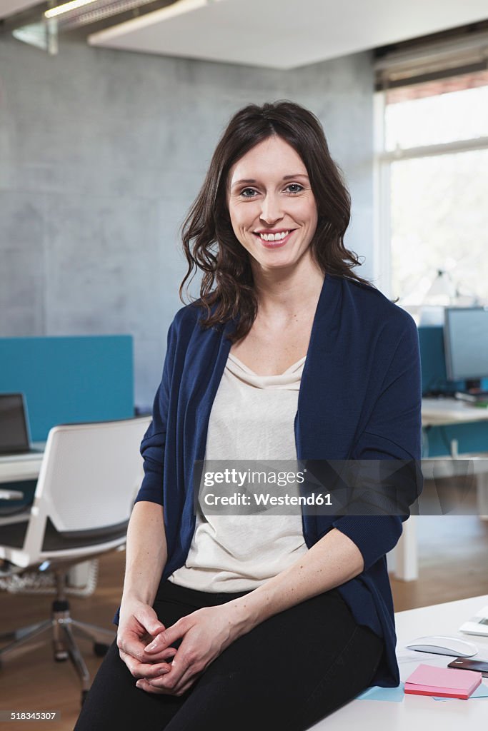 Portrait of smiling woman sitting at her workplace in the open space office