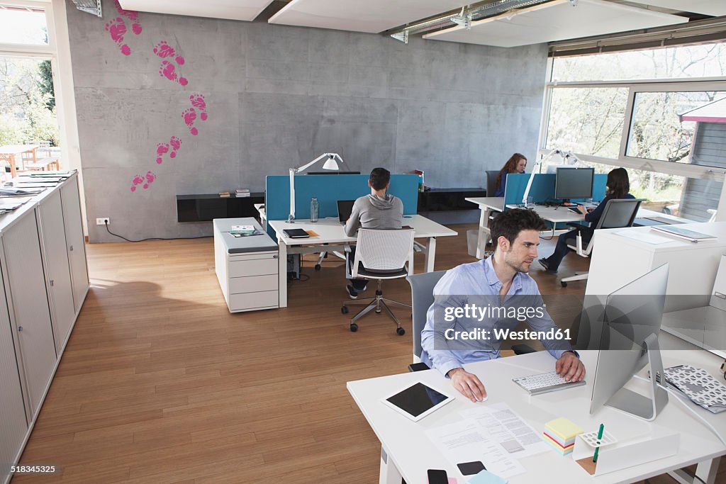 Four colleagues working in modern open space office