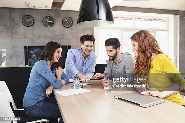 four creative people at business conference in the office - clock person desk stockfoto's en -beelden