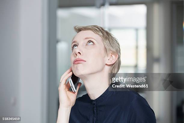 germany, munich, businesswoman in office, using smart phone - impatient fotografías e imágenes de stock