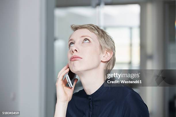 germany, munich, businesswoman in office, using smart phone - ongeduldig stockfoto's en -beelden