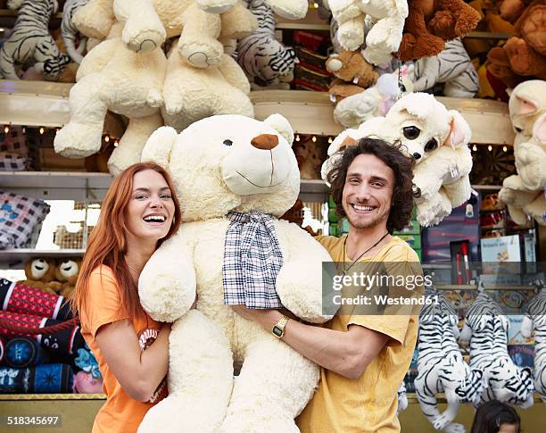 happy young couple on a funfair with large teddy bear - big toothy smile stock pictures, royalty-free photos & images