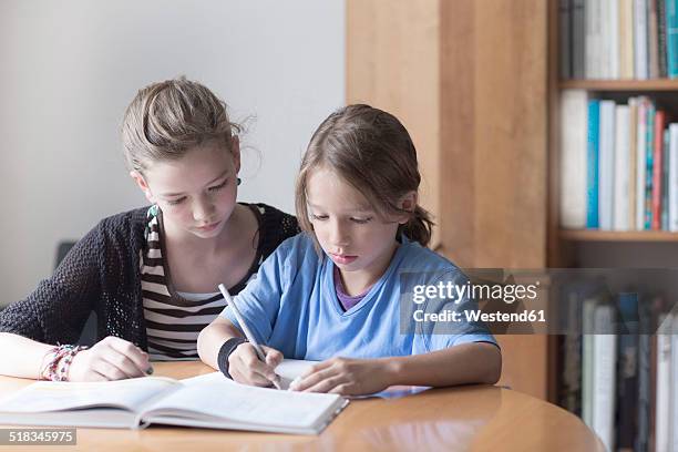 sister helping her little brother by doing his homework - 13 pencils stock-fotos und bilder