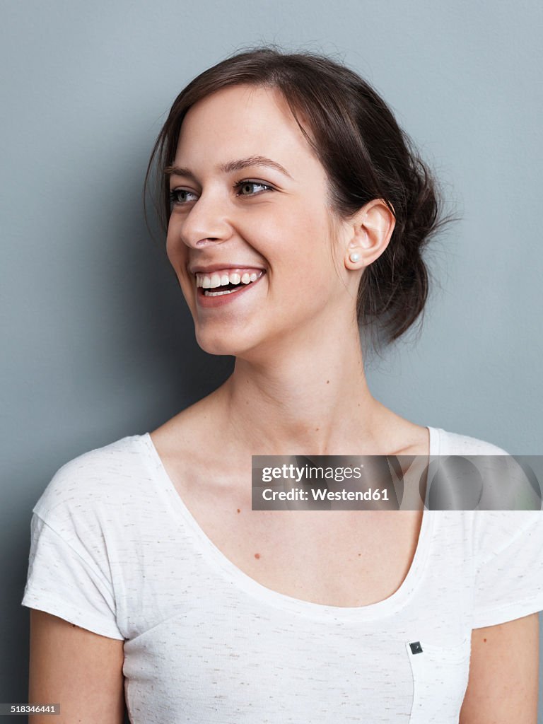 Portrait of smiling brunette woman in front of gray background
