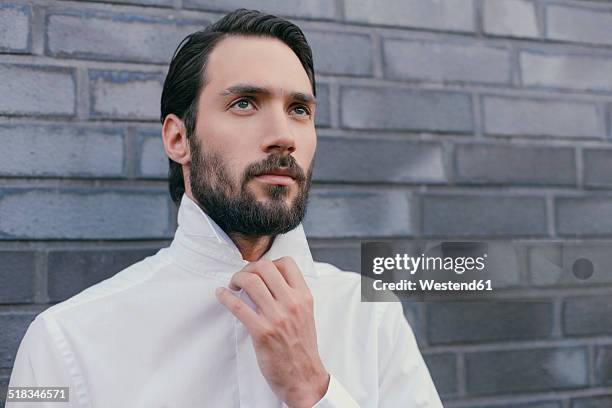 portrait of young man folding up the collar of his shirt - buttoning stock pictures, royalty-free photos & images