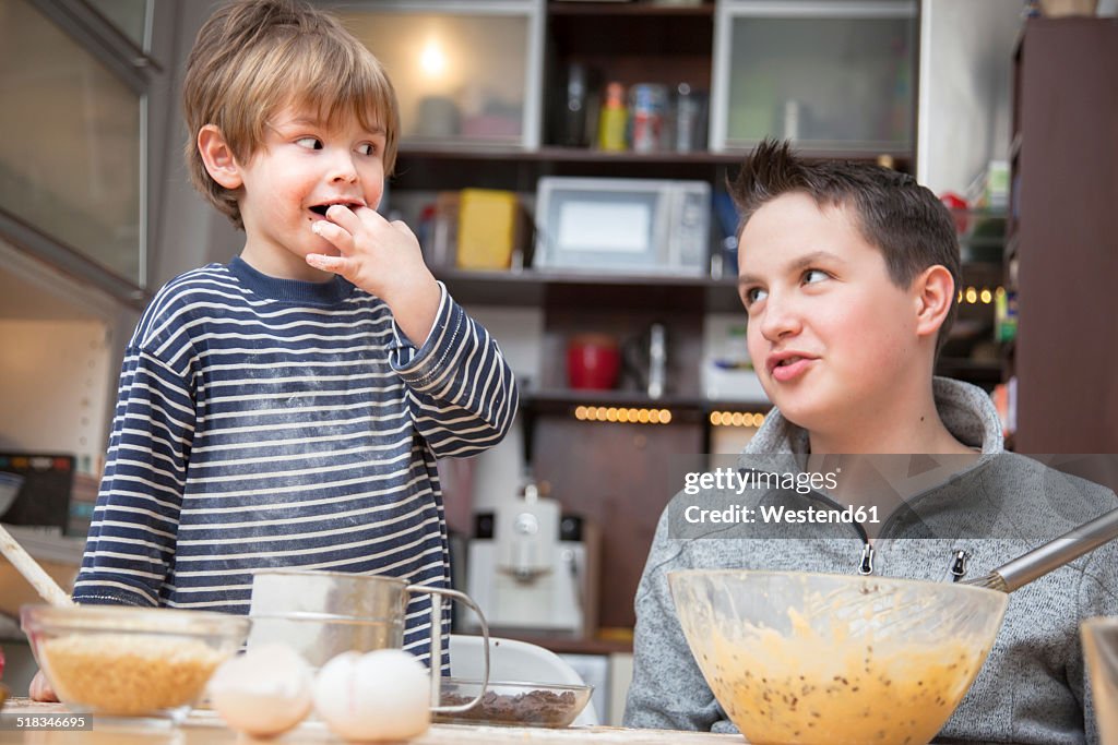 Two brothers baking a cake together at home