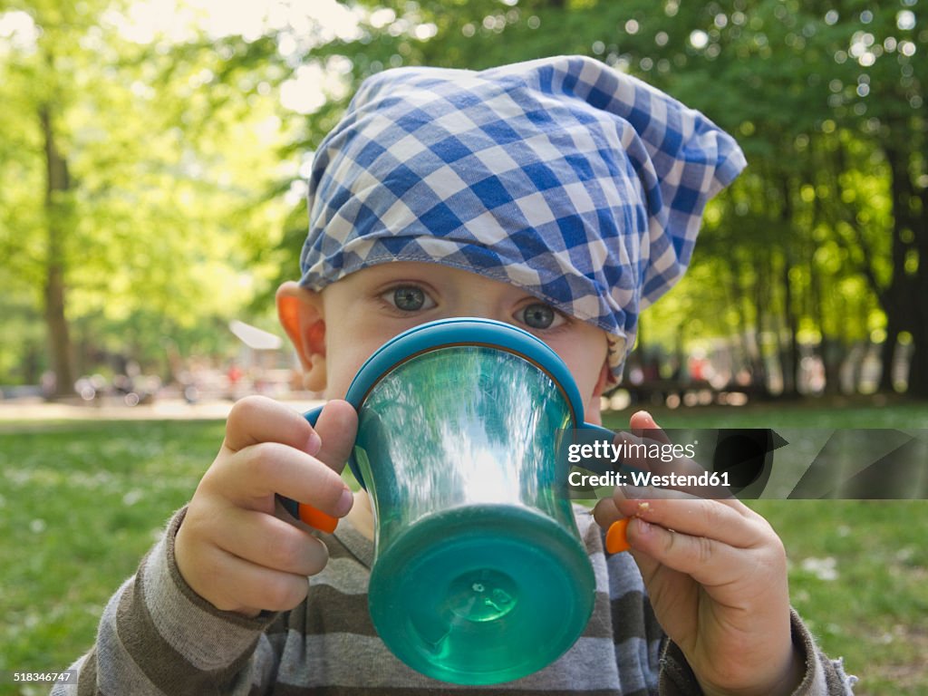 Baby boy wearing headscarf drinking