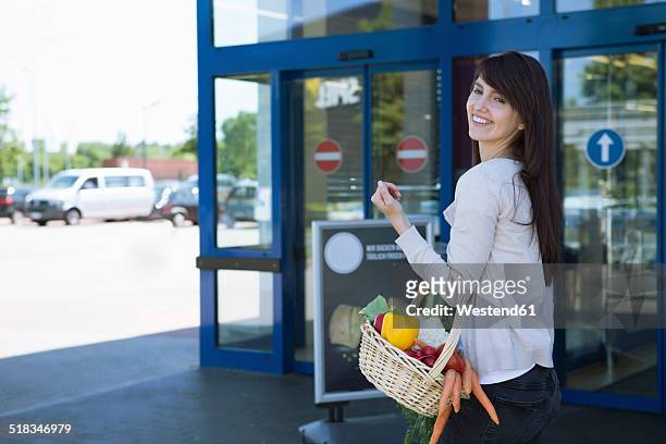 portrait of smiling young woman carrying basket with fresh vegetables - parking entrance fotografías e imágenes de stock