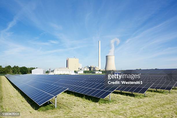 germany, north rhine-westphalia, petershagen-lahde, field with solar panels and a coal-fired power station in the background - north rhine westphalia stock pictures, royalty-free photos & images