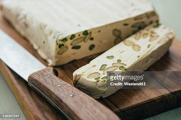 sliced home-made turron with pistachios and almonds on wooden board - nougat stock-fotos und bilder