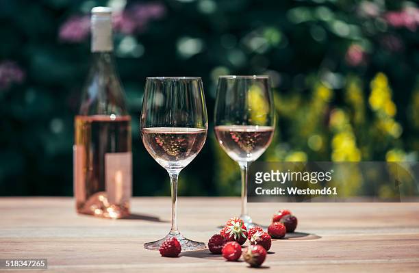 two glasses of rose wine, wine bottle, strawberries and raspberries on wooden table - wine nobody stock-fotos und bilder