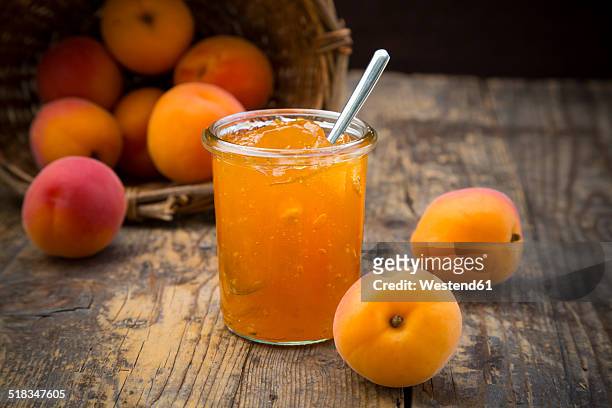 glass of apricots jam and apricots on wood - aprikosenkonfitüre stock-fotos und bilder