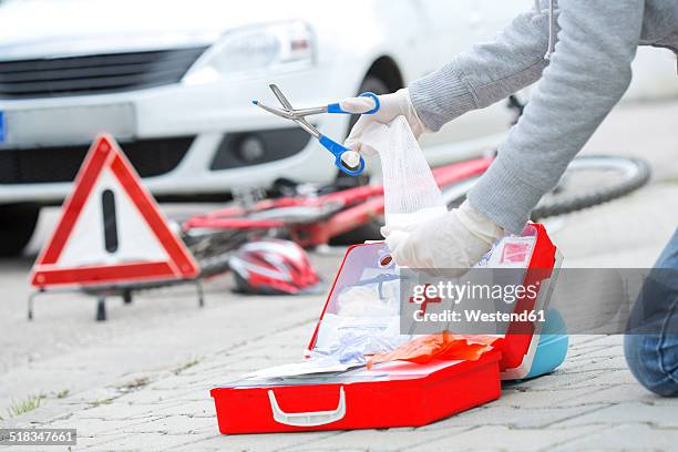 woman applying first aid at crash scene, partial view - first aid kit stock-fotos und bilder