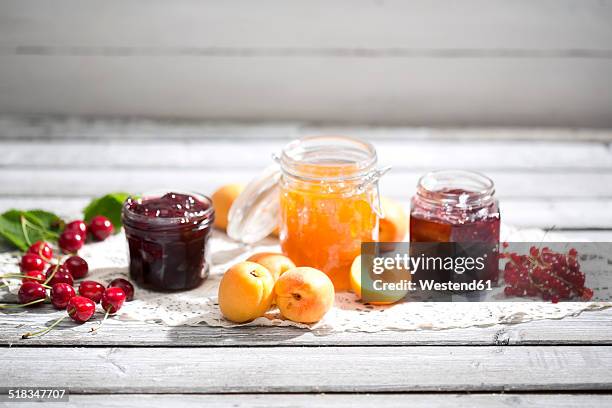 cherry jam and cherries, apricot jam and apricots, currant jam and red currants on dolly - sauerkirsche stock-fotos und bilder