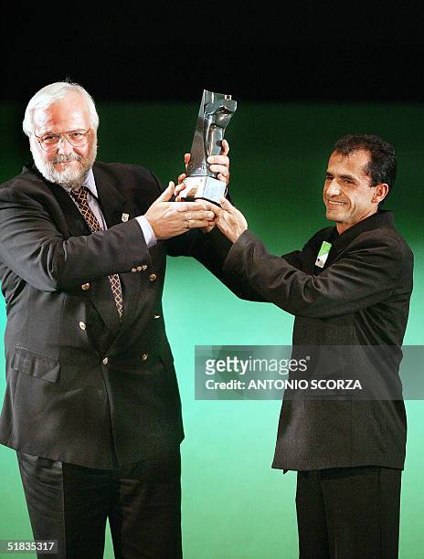 Greek national Polyvios Kossivas receives a trophy from Brazilian marathon runner Vanderlei Cordeiro de Lima 07 December, 2004 in Rio de Janeiro,...