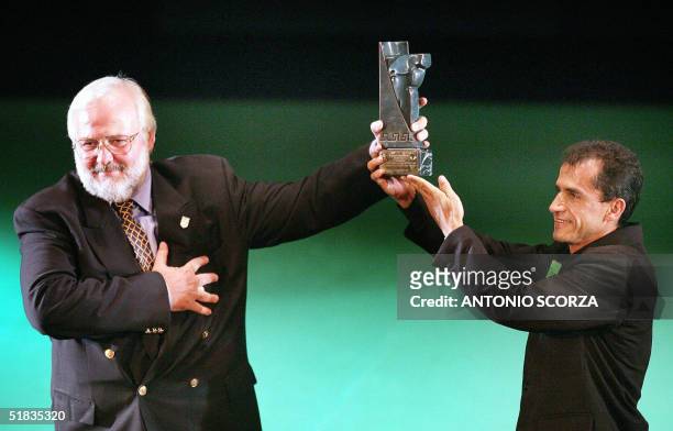 Greek national Polyvios Kossivas receives a trophy from Brazilian marathon runner Vanderlei Cordeiro de Lima 07 December, 2004 in Rio de Janeiro,...