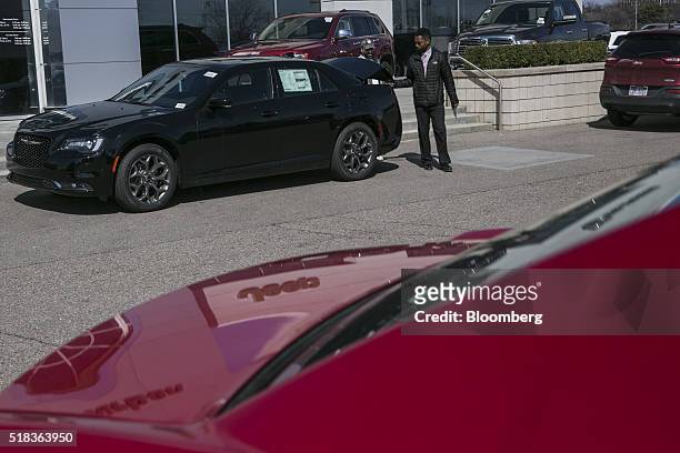 Sales representative opens the trunk of a Fiat Chrysler Automobiles NV Chrysler 300 mid-size vehicle outside of Suburban Chrysler Dodge Jeep Ram of...