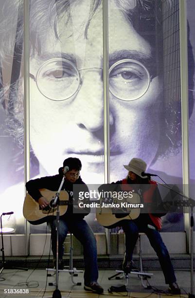 Two Japanese fans perform in front of a giant photograph of John Lennon at the John Lennon Museum on December 8, 2004 in Saitama, Japan. Fans...