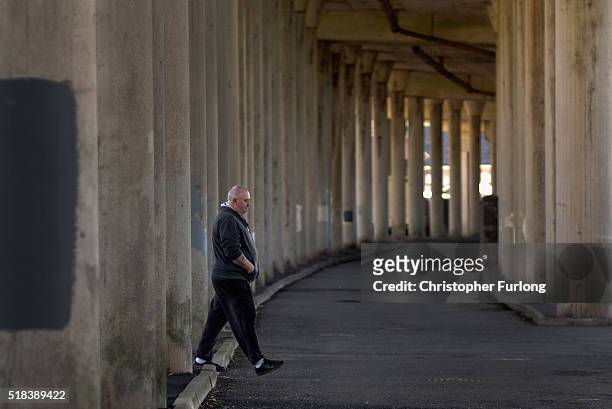 Man walks past the supporting pillars of the M4 motorway in Port Talbot on March 31, 2016 in Port Talbot, Wales. Indian owners Tata Steel has put its...