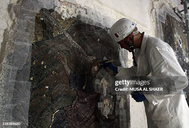 An Italian expert restores a wall of icons under renovation at the Church of the Nativity in the biblical West Bank town of Bethlehem on February 27,...