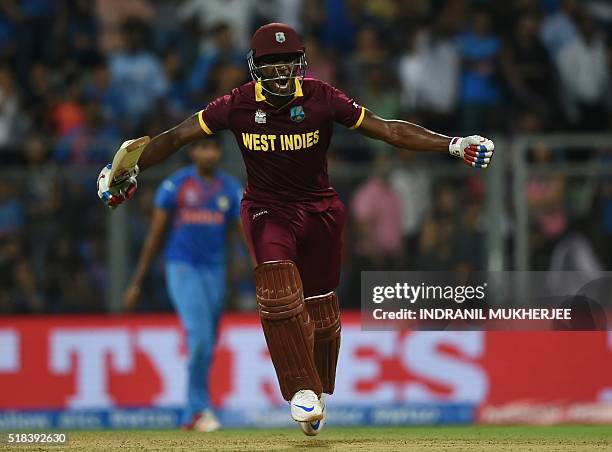 West Indies's Andre Russell celebrates after scoring the winning runs during the World T20 men's semi-final match between India and West Indies at...