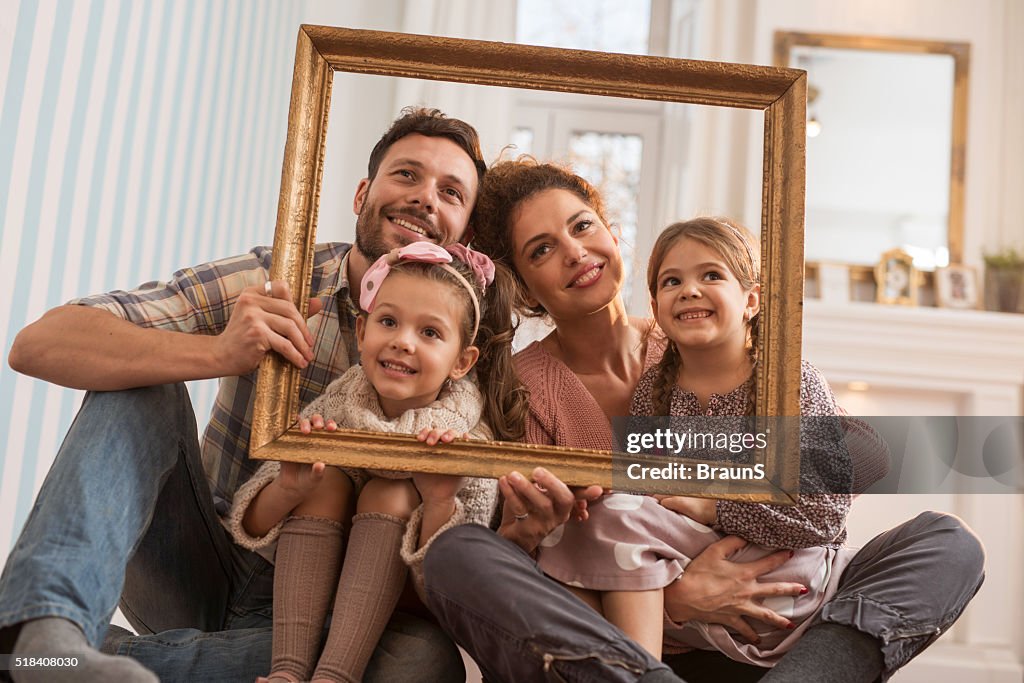 Família sorridente um divertir-se com uma foto quadro em casa.