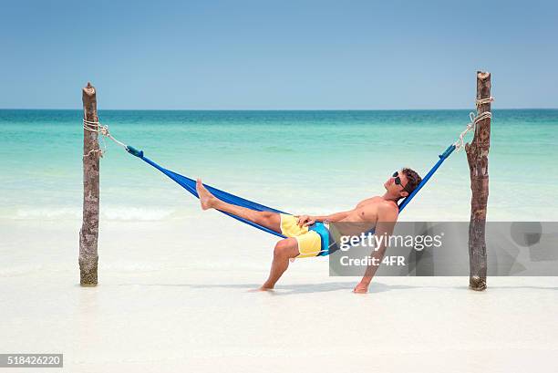 man relaxing in a hammock on a tropical island - mens shorts stock pictures, royalty-free photos & images