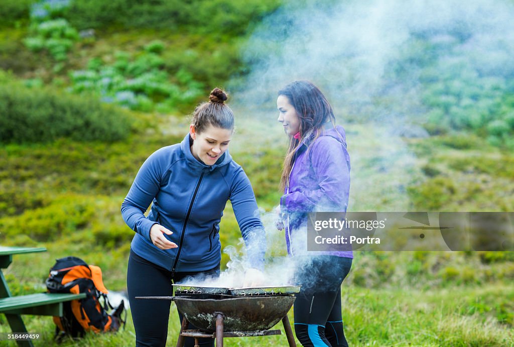 Women barbecuing on grassy field