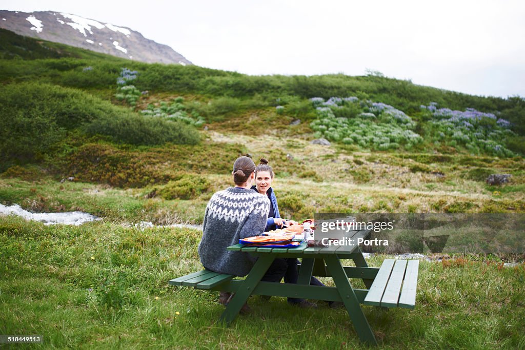 Hiking couple having food at table on mountain