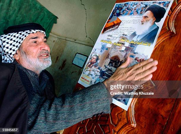 Supporter of Shiite cleric Ayatollah al-Sistani makes blessings as a poster urging for participation in the coming elections is seen inside the...