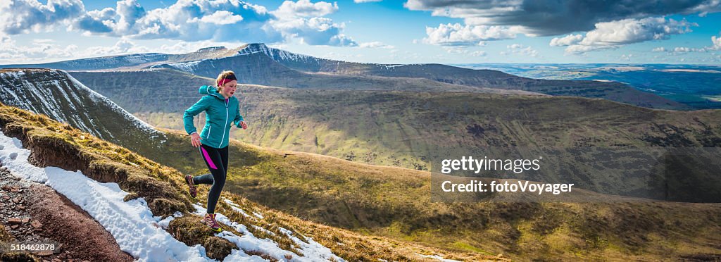 Young woman running on wilderness trails on mountain ridge panorama