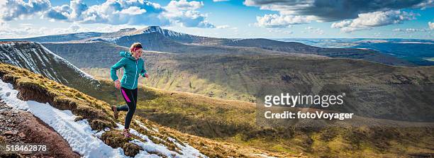 young woman running on wilderness trails on mountain ridge panorama - springtime exercise stock pictures, royalty-free photos & images