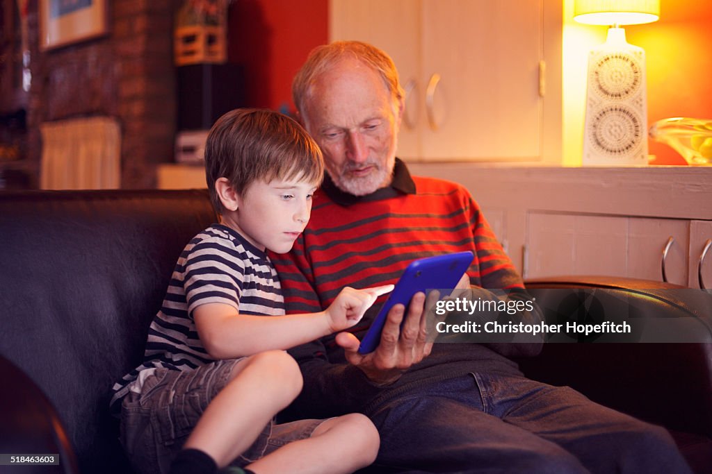 Boy using a tablet computer with Grandad