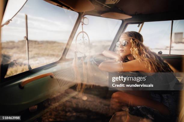 road trip hipster girl sitting in retro van at beach - hippie stockfoto's en -beelden