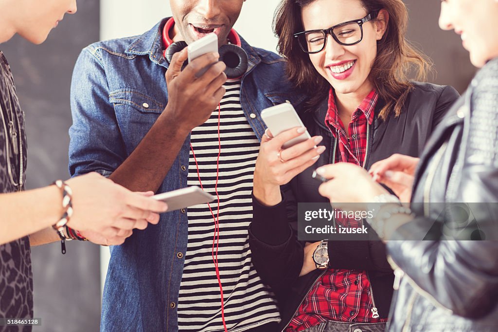 Friends using smart phones, close up of hands