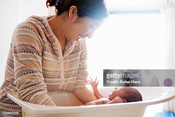 mother taking care of her baby - bañando bebe fotografías e imágenes de stock