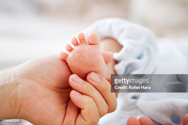 mother holding her baby's foot - heels hand stock-fotos und bilder