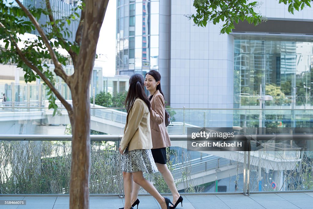 Two businesspeople outdoors walking by building