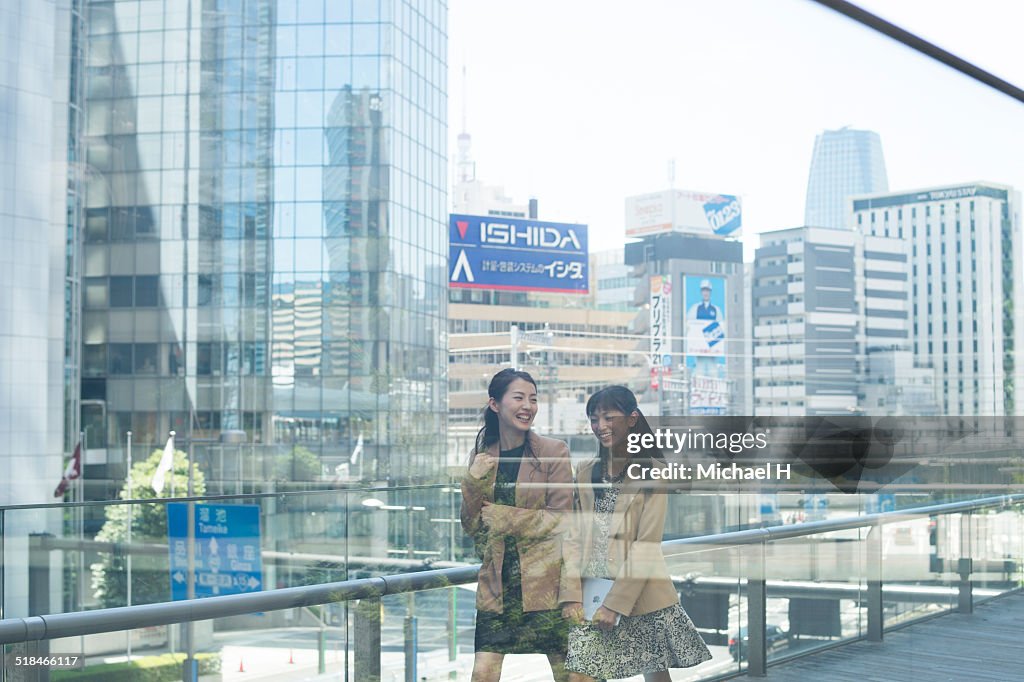 Two businesspeople outdoors walking by building