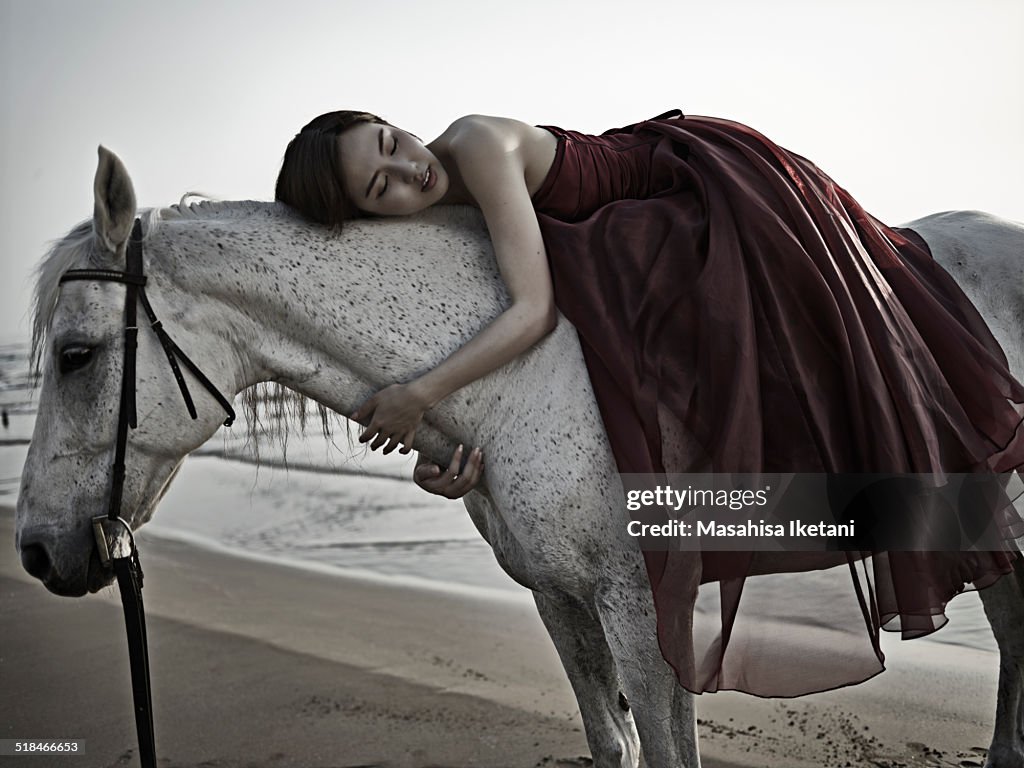 Horse and woman wearing a dress in the sea